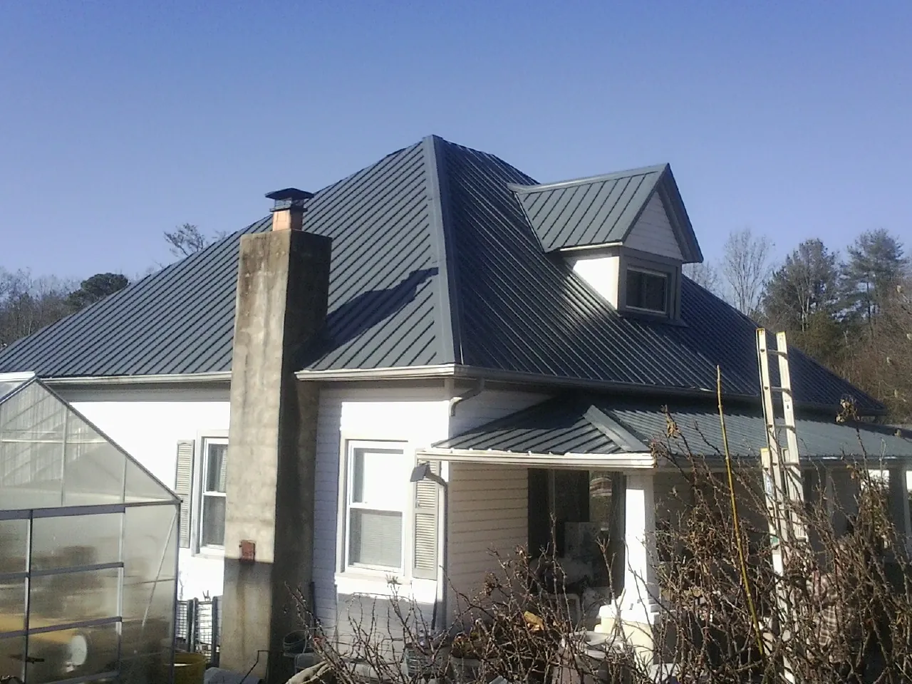 Dark blue standing seam metal roof on a white farmhouse with dormer — Slate & Tile Roof Repair by Roofing Brothers in Barrett