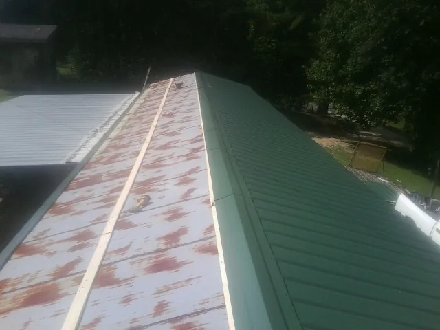 Old rusted panels beside newly installed green metal roofing — Wind Damage Roof Repair by Roofing Brothers in Barrett
