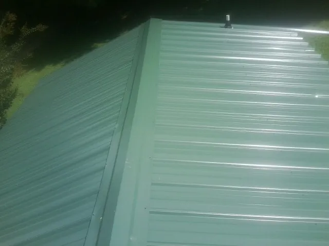 New green metal panels meeting at the ridge of a roof — Flat Roof Repair work by our crew in Barrett