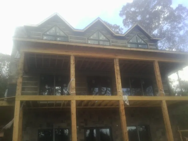 Dormers and porch framing on a large log home under construction — Roof Coating work by our crew in Barrett