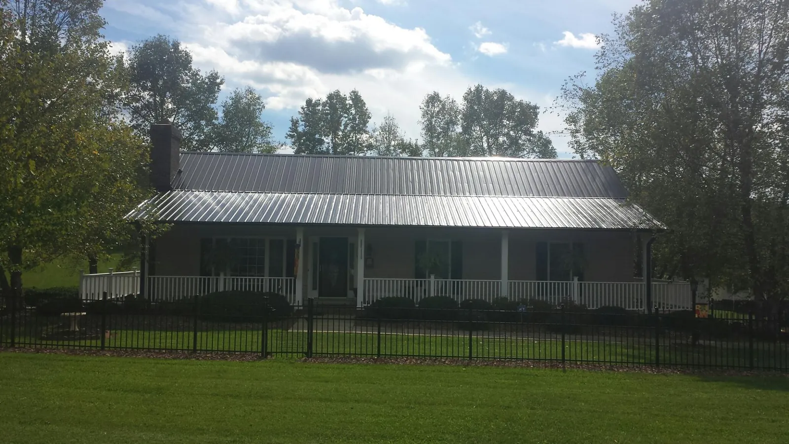 Gray metal roof on a brick ranch with a full width front porch — Gutter Guard Installation work by our crew in Barrett