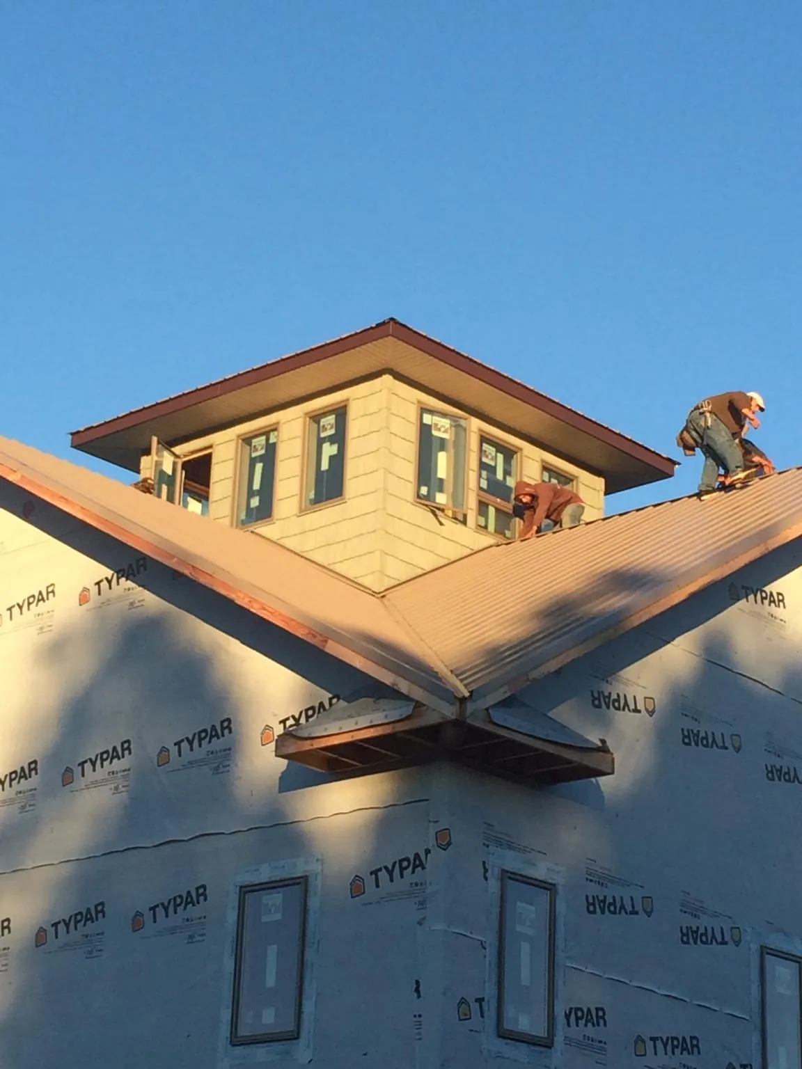 Roofers working around a rooftop cupola on a new metal roof at sunset — Roof Waterproofing in Barrett by Roofing Brothers